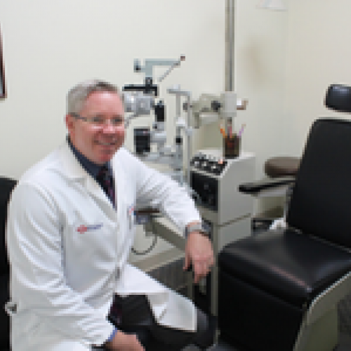 Dr. Marc Peden smiling in office next to black chair